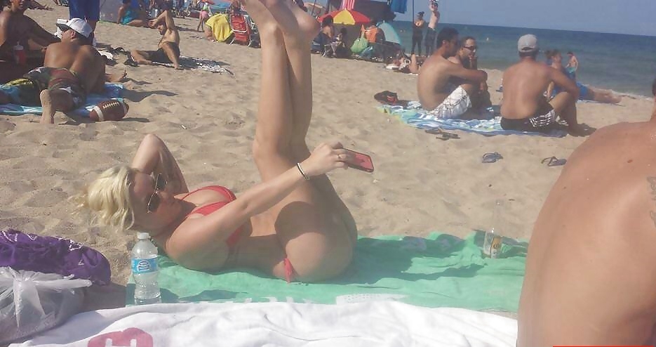 На пляже девушка снимает у себя между ног