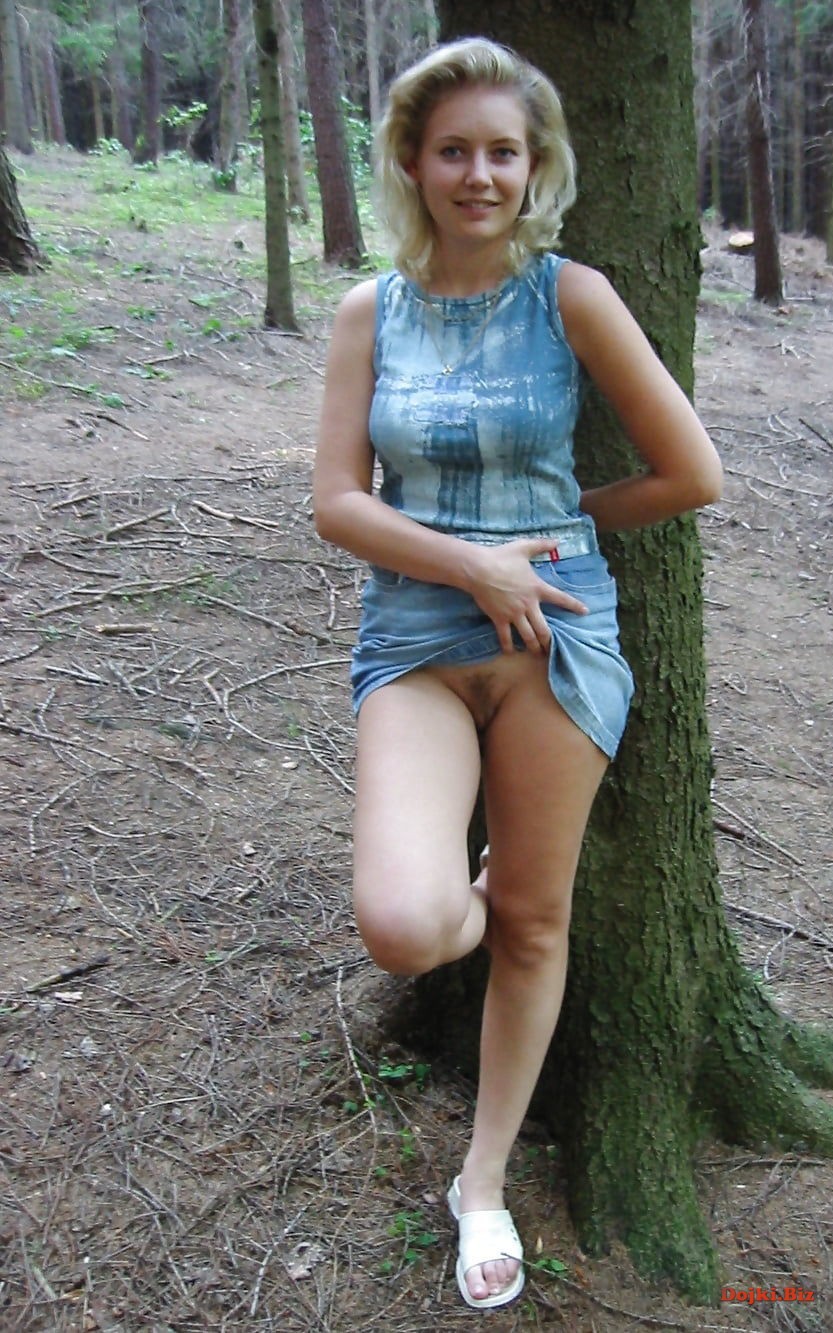В лесу за деревом девушка показывает писю
